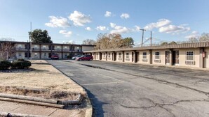 A motel with a parking lot, a building with multiple windows, and a clear sky. - Bald Knob AR|King Bed|Smoking (Bald Knob AR)