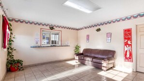 Un'ampia stanza con una grande finestra, un divano in pelle marrone, una scrivania della reception e uno striscione decorativo rosso al muro.