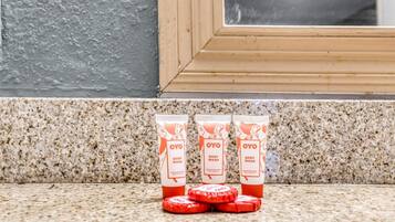 Three OYO body wash bottles and four red circular objects on a granite countertop.
