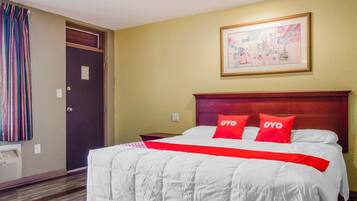 Hotelkamer met een bed, hoofdeinde, nachtkastje, een deur en een aan de muur hangend schilderij.