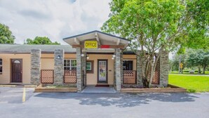 A building with a sign reading 'OFFICE OPEN' at the entrance, stone pillars, and a covered entrance area.