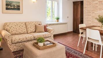 Ein Wohnzimmer mit einer Couch, einem Hocker und einem Essbereich mit Stühlen und einem Tisch.