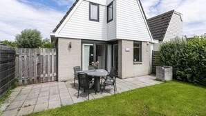 Een modern huis met een terras, een eettafel en stoelen.