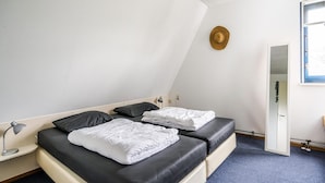 Een kamer met twee bedden, een bureau, een lamp en een raam.