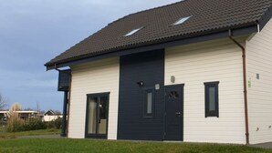 A single-story building with a dark roof, a central door, and a small window on the upper floor. - Pavilion L'etage Sauna 10 (Susteren)