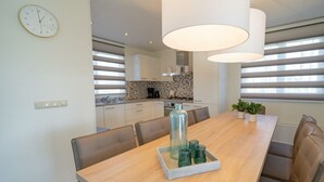 A modern kitchen with white cabinets, a tiled backsplash, and a window with horizontal blinds. - Pavilion L'etage Sauna 10 (Susteren)