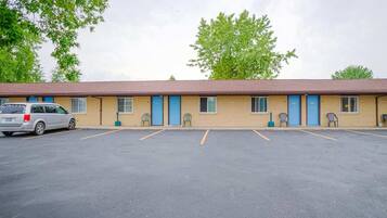A motel with a parking lot, a single-story building, and a car parked in front.