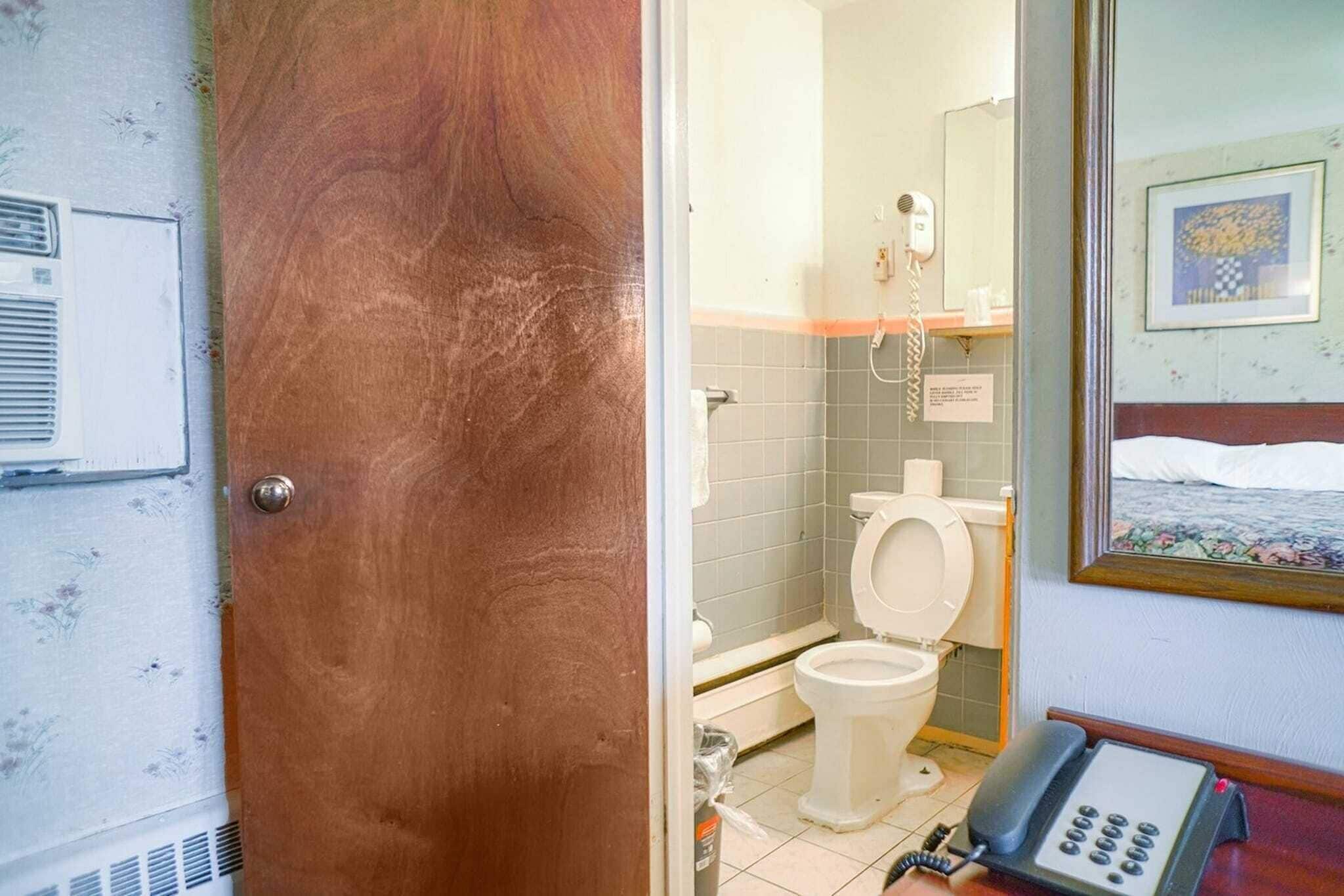 A bathroom with a toilet, a shower, and a telephone.