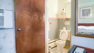A bathroom with a toilet, a shower, and a telephone.