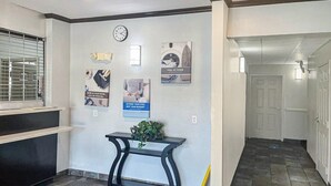 A hallway with a clock, posters, a bench, and a door.