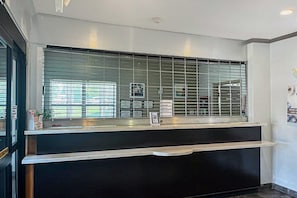 Taulell de recepció amb una partició de vidre, un codi QR i un cartell que ofereix un descompte.
