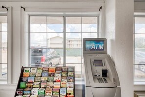 An ATM machine and a display of travel brochures in a room with large windows. - Accessible King Bed|Baton Rouge LA (Baton Rouge LA)