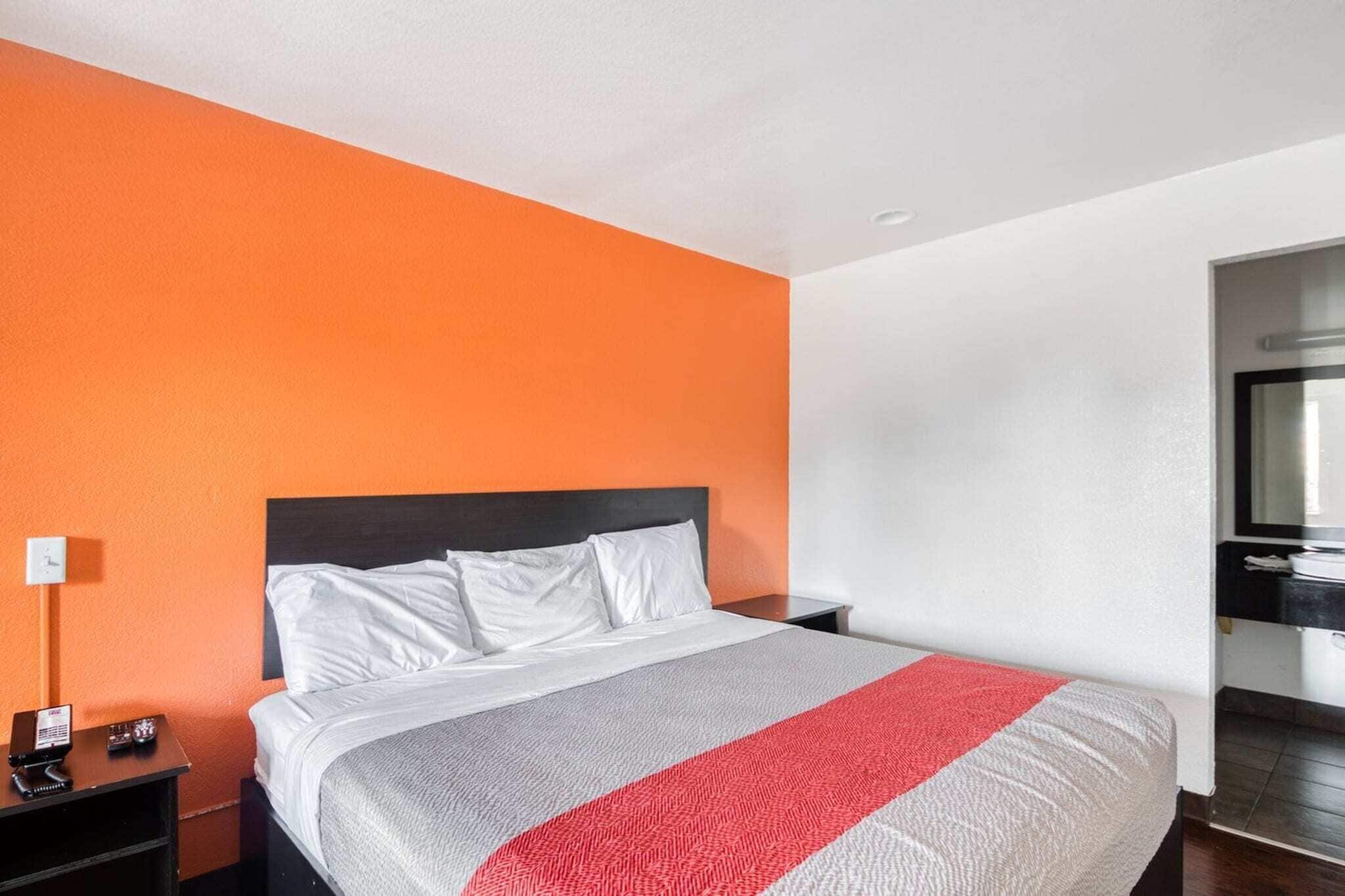 A hotel room with a bed, a nightstand, a telephone, and a mirror.