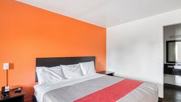 Een hotelkamer met een bed, nachtkastje, telefoon en spiegel.