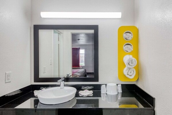Une salle de bain avec un lavabo blanc, un miroir et un porte-serviettes jaune.