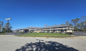 Kaksikerroksinen motelli, jossa on tasakatto, parkkipaikka ja kyltti, jossa lukee nimellä «Brookville Inn».