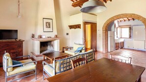 A spacious living area with a fireplace, a dining table, and a TV. - Monacianello -Fontebelvedere wine estate (Ponte A Bozzone)