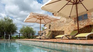 A clear swimming pool with lounge chairs and umbrellas, surrounded by stone walls and trees. - Monacianello -Fontebelvedere wine estate (Ponte A Bozzone)