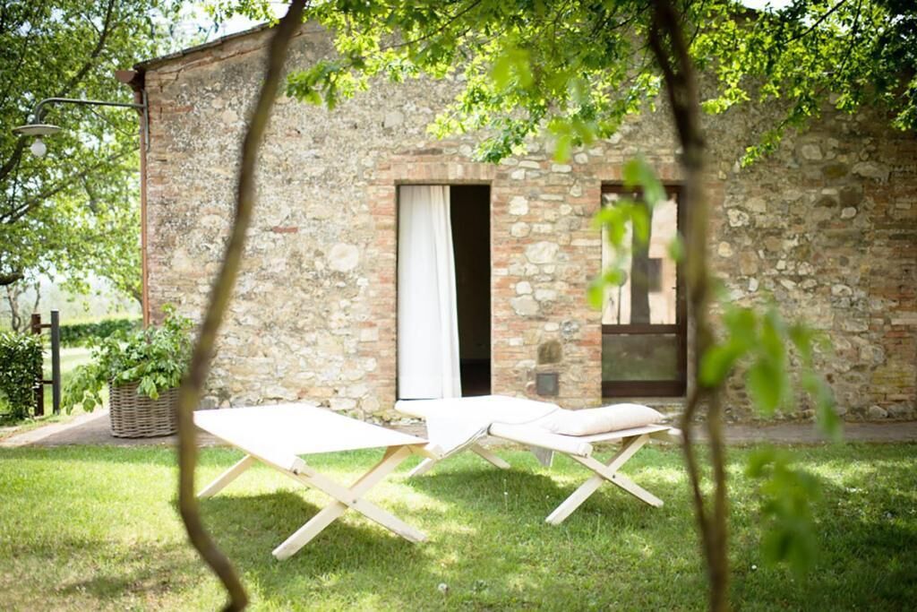A stone building with a door and windows, a grassy lawn, and two wooden lounge chairs.