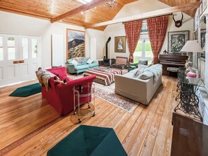 Un salon chaleureux avec un parquet, un fauteuil rouge, un canapé bleu et un canapé blanc.