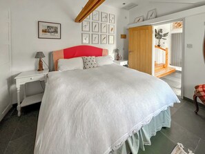 A bedroom with a large bed, a wooden wardrobe, a bedside table with a lamp, and framed pictures on the wall. - 2 bedroom accommodation in Colne Engaine (Colne Engaine)