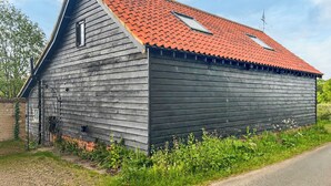 A wooden barn with a red roof, a small attached structure, and a metal gate.