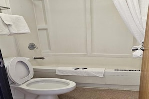 Un baño con inodoro, bañera y cortina de ducha.