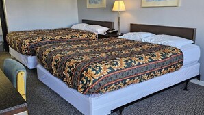 Habitació d'hotel amb dos llits, un escriptori, una cadira, una làmpada i dos quadres a la paret.