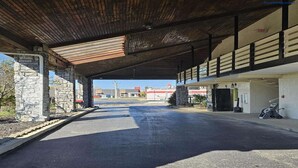 Zona d'aparcament coberta amb pilars de pedra, un carrer pavimentat i un edifici amb el rètol 'Office'.