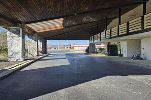 A covered parking area with stone pillars, a paved road, and a building with an 'Office' sign. - 2 Queen Beds Non-Smoking (Brookville, OH)