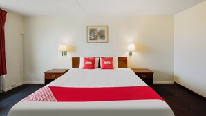 A hotel room with a bed, two bedside tables, two wall-mounted lamps, a framed picture, and a red and white bedspread. - King Bed | Non Smoking (Doswell VA)