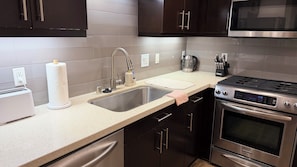 A modern kitchen with a stainless steel sink, a built-in oven, and a microwave.