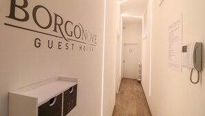 Käytävällä on kyltti, jossa lukee ”Borgonove-vierastalo”, ja seinälle on kiinnitetty puhelin.