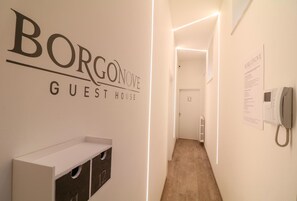 Ein Korridor mit einem Schild für 'Borgonove Guest House' und einem an der Wand befestigten Telefon.