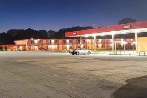 A gas station with a car parked in front, multiple fuel pumps, and a red canopy.