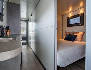 A compact bedroom with a bed, a window, and a built-in desk with a sink. - Kamperland Water Lodge (Kamperland)
