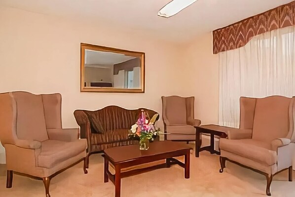 A living room with two sofas, a coffee table, a mirror, and a window with curtains.