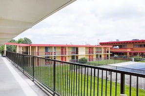 A multi-story hotel with a red roof, a courtyard, and a fenced balcony.