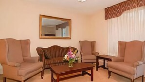 A living room with two sofas, a coffee table, a mirror, and a window with curtains.