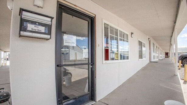A motel with a drop box, security sign, and a covered walkway.