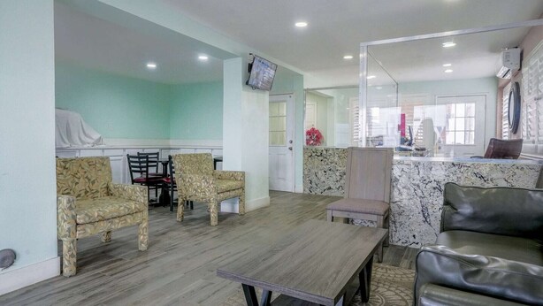A living area with patterned chairs, a wooden table, a leather sofa, and a kitchen area with a marble countertop.