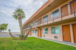 Un motel de varios pisos con fachada de ladrillo, balcones y una palmera en primer plano.