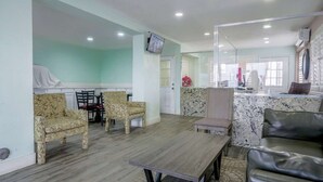 A living area with patterned chairs, a wooden table, a leather sofa, and a kitchen area with a marble countertop. - 2 Full Beds Non-Smoking (Buttonwillow, CA)
