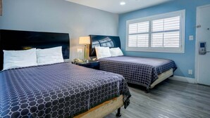 A hotel room with two beds, a nightstand, a lamp, and a window with blinds. - 2 Full Beds Non-Smoking (Buttonwillow, CA)