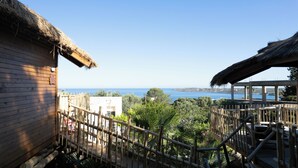 A wooden building with a thatched roof, a wooden fence, and a view of the sea.