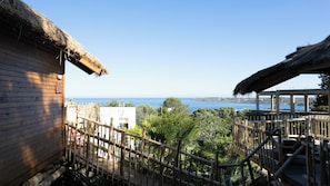 A wooden building with a thatched roof, a wooden fence, and a view of the sea.