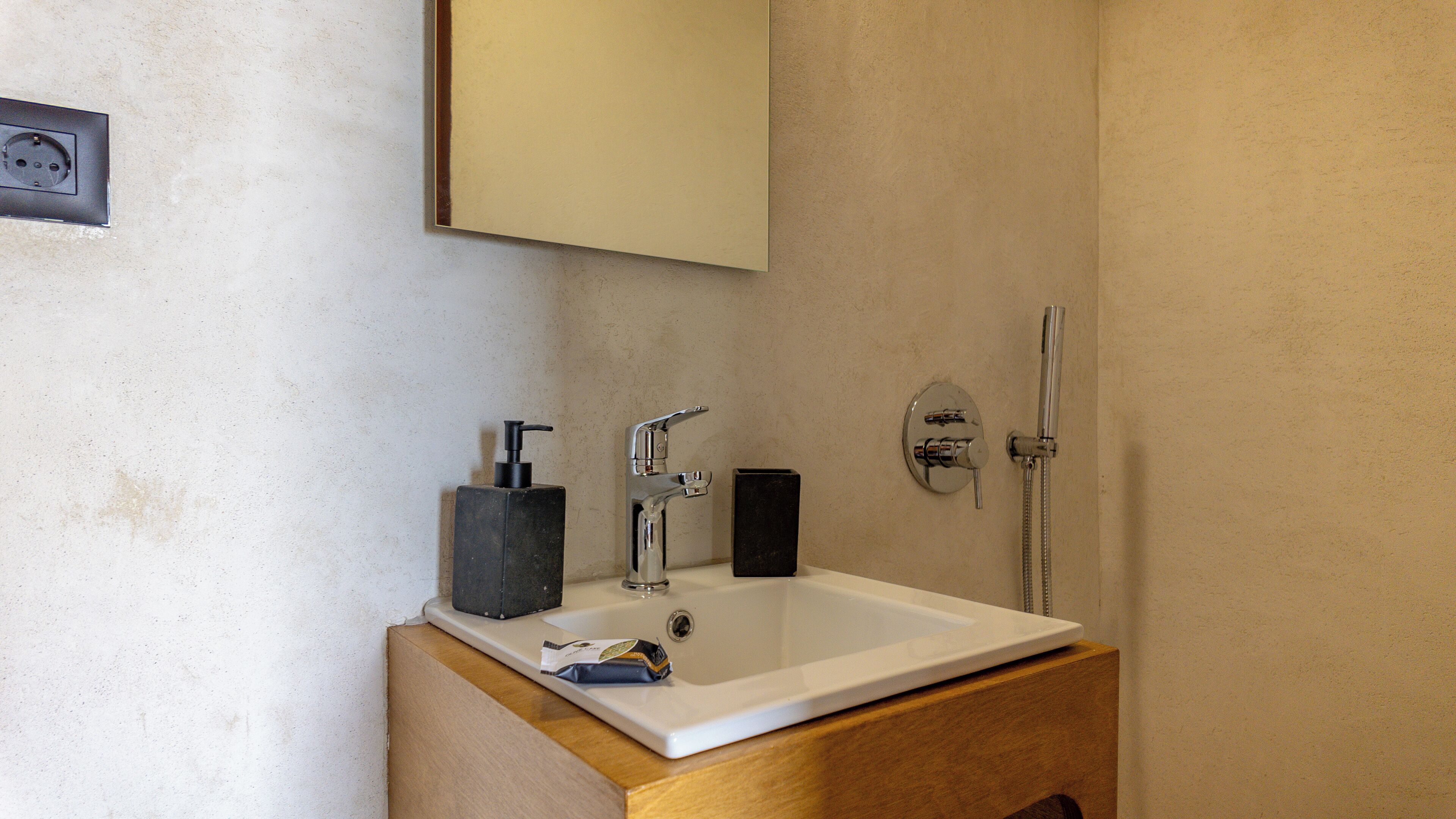 A bathroom with a white sink, black soap dispenser, and a silver faucet.