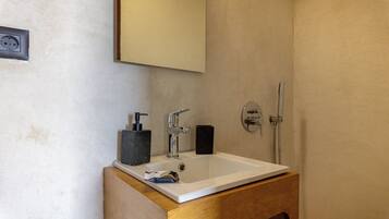 Un bagno con lavandino bianco, dispenser per sapone nero e rubinetteria argentata.