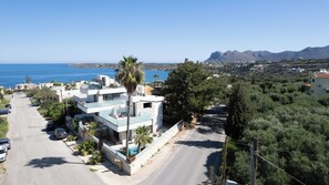 Un edificio moderno de varios pisos con piscina, situado cerca de la costa y con vistas al mar y a las montañas.