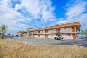 A motel with a two-story structure, a parking lot, and a clear sky.